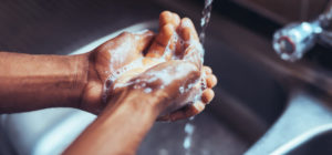 Henkilö pesemässä käsiä hanan alla