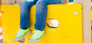 Lapsi istumassa keltaisella leikkitelineellä
