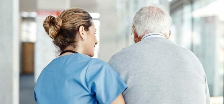 Terveysalan ammattilainen avustaa ikäihmistä kävellessä