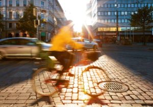 Pyöräilijä keltaisessa takissa vilahtaa kameran ohitse kaupungissa