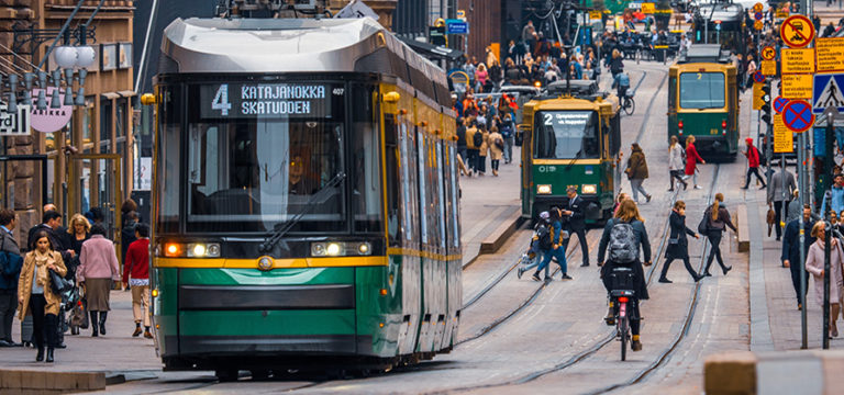 Helsingin keskustassa raitiovaunuja, jalankulkijoita ja pyöräilijöitä.
