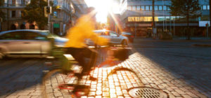 Pyöräilijä keltaisessa takissa vilahtaa kameran ohitse kaupungissa